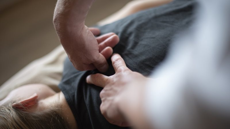 A chiropractor applying a hands-on spinal adjustment during a treatment session