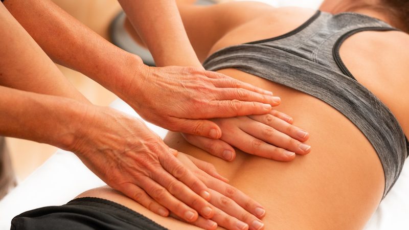A therapist's hands performing therapeutic massage on a patient's back